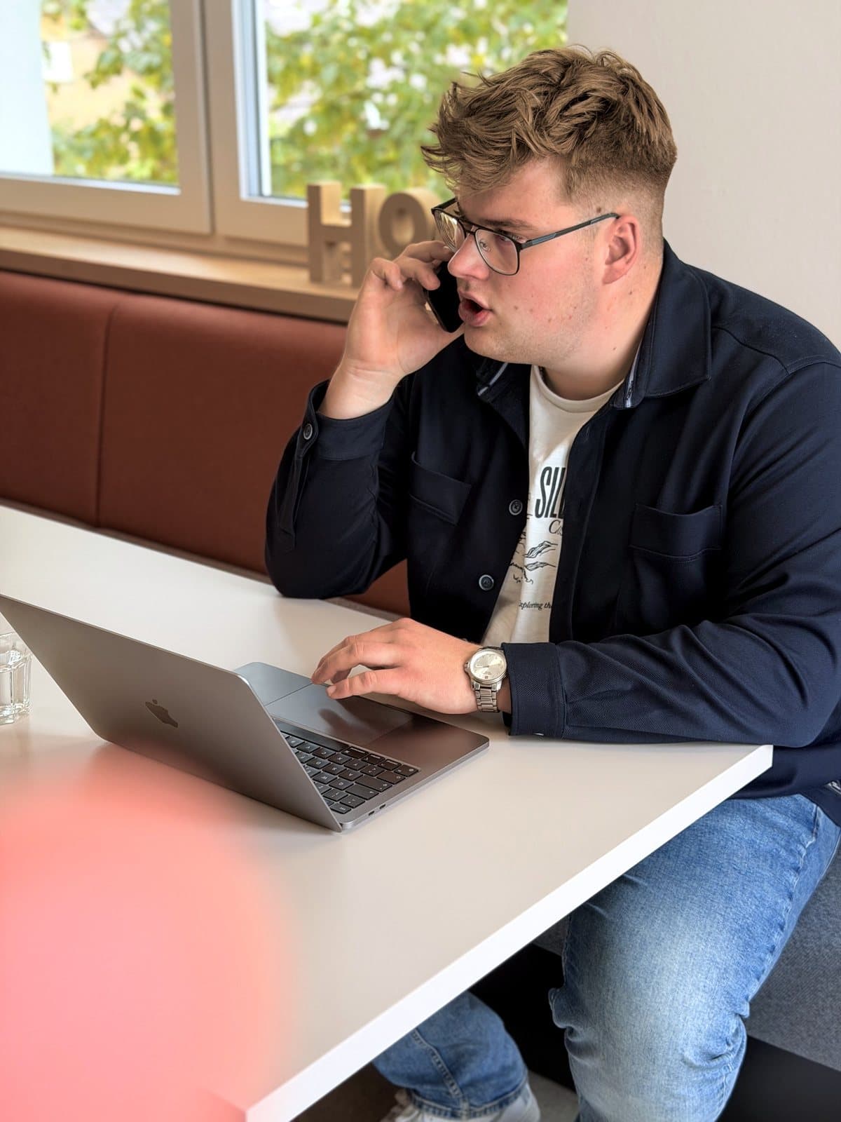 Paul Budde am Telefon, den Laptop vor sich.