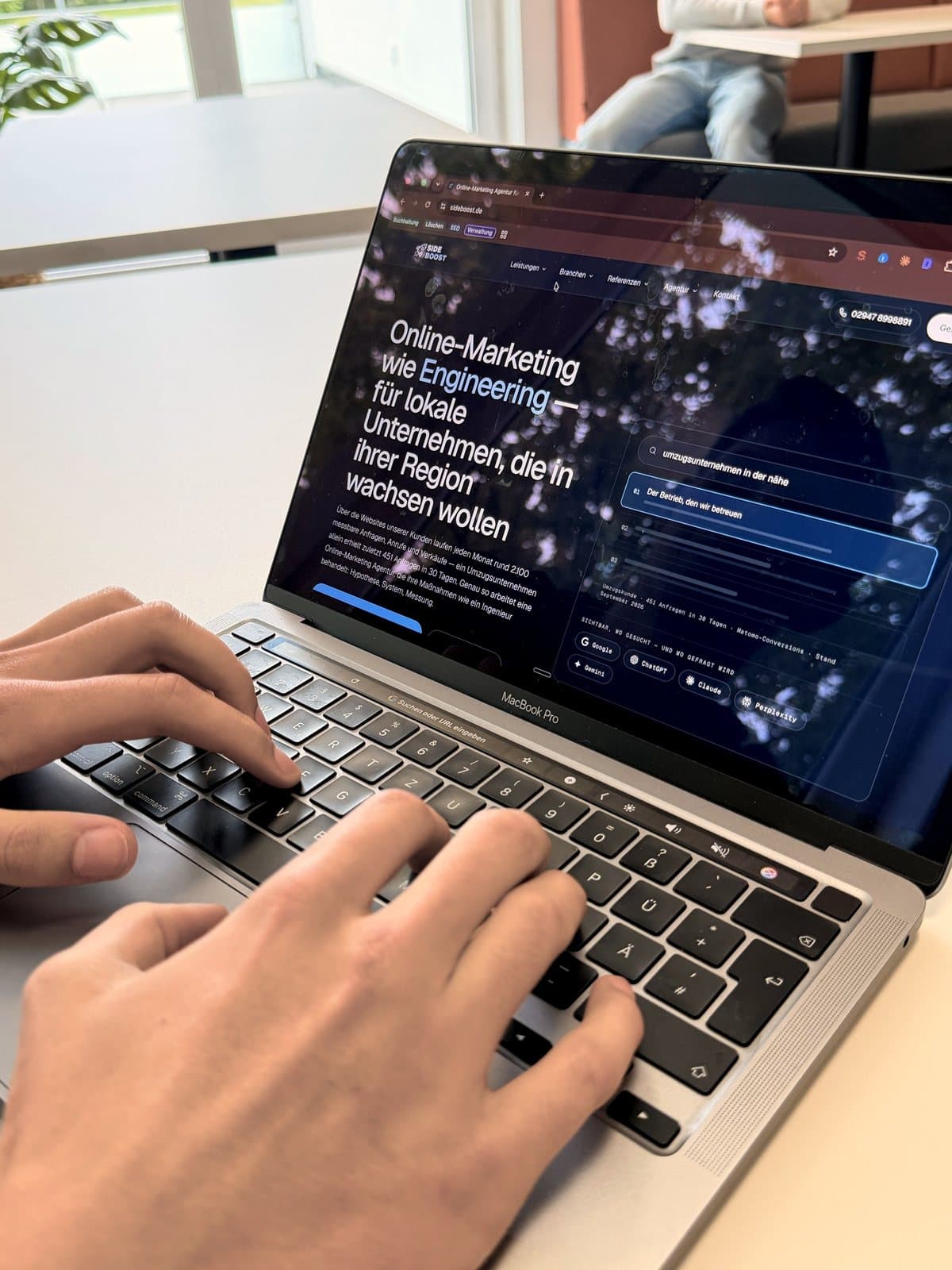 Zwei Hände auf einer MacBook-Tastatur, auf dem Bildschirm die Startseite von Side Boost.