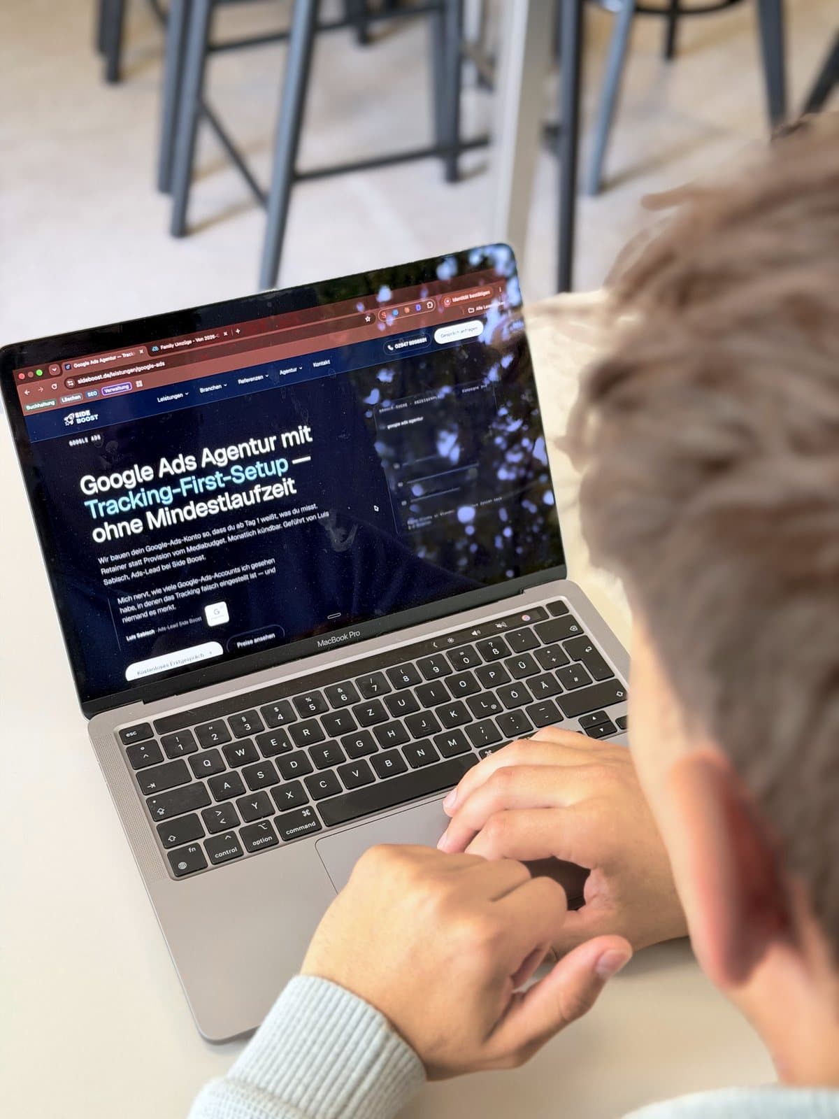 Blick über Luis Sabischs Schulter auf einen Laptop, auf dem die Google-Ads-Seite von Side Boost geöffnet ist.