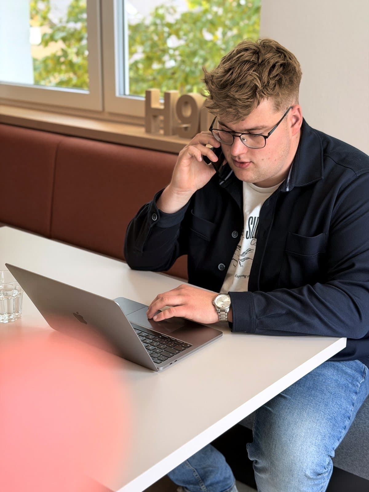 Paul Budde am Telefon, den Laptop vor sich.