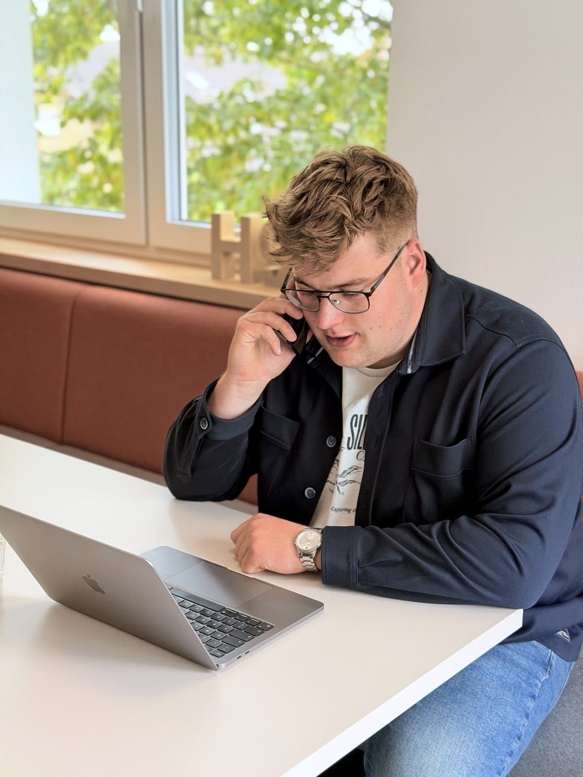 Paul Budde am Telefon, den Laptop vor sich.