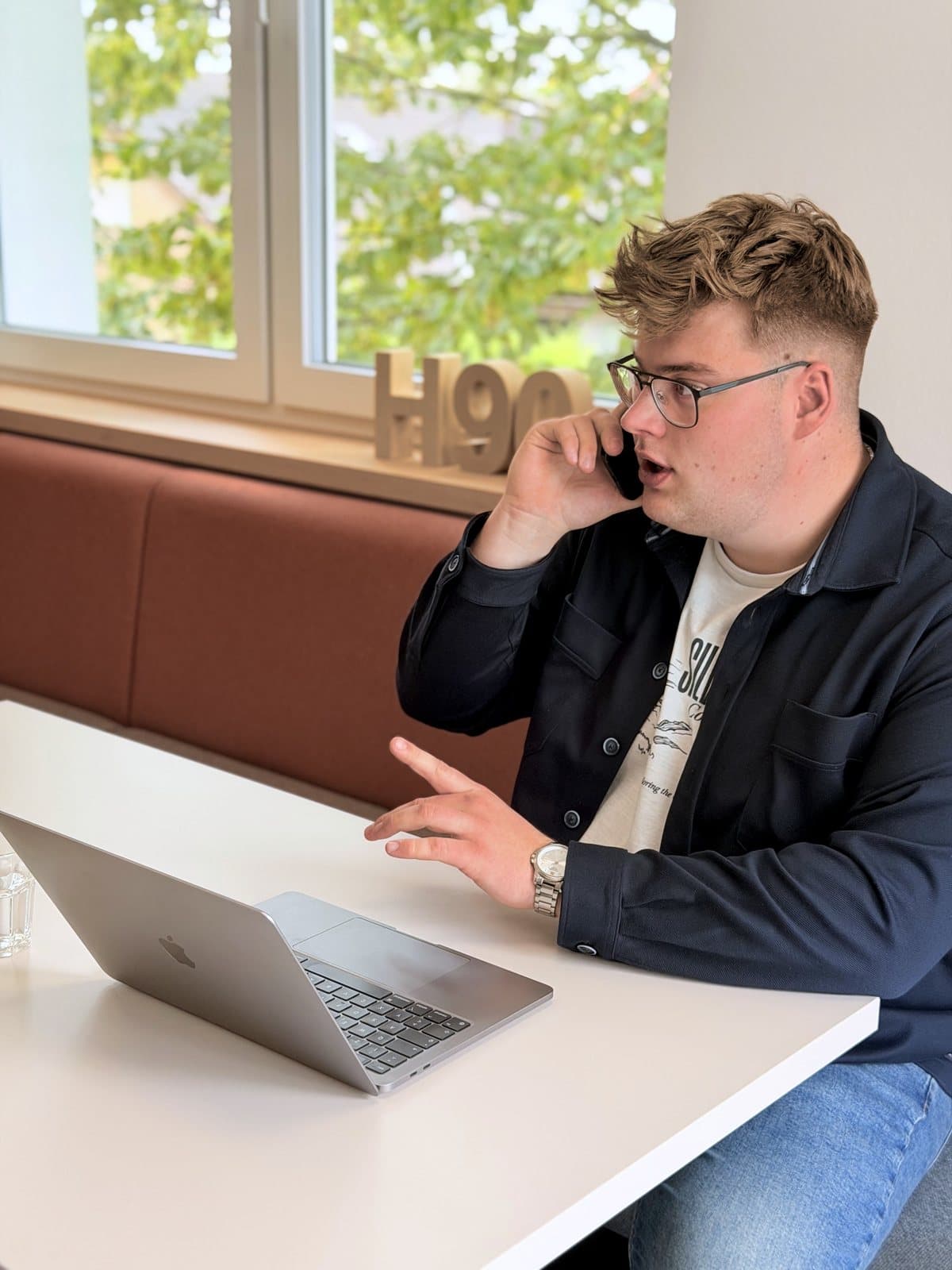 Paul Budde telefoniert, die freie Hand auf dem Tisch.