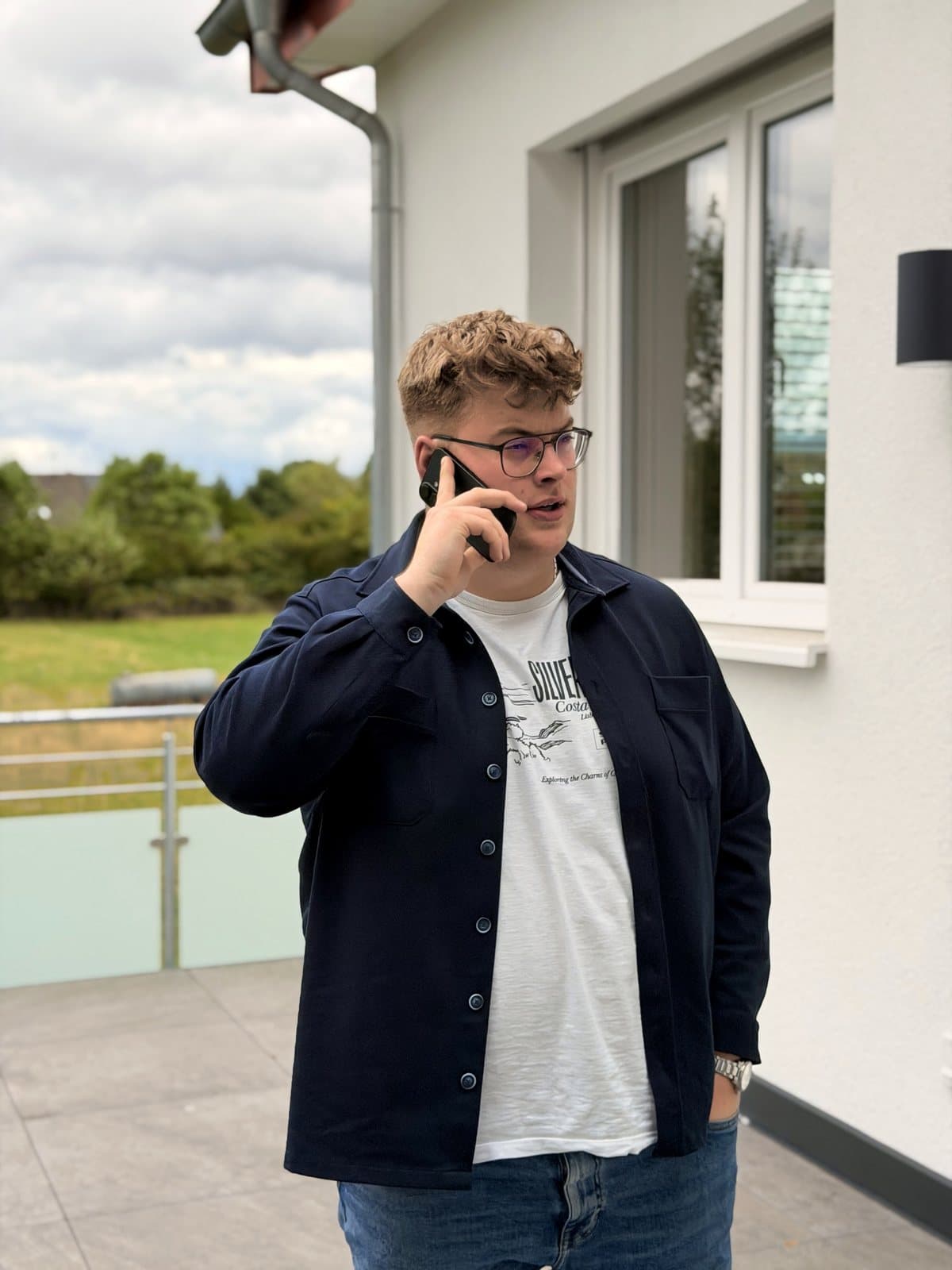 Paul Budde draußen am Telefon, vor dem Büro.